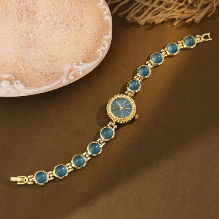 Montre vintage pour femme en or et pierres vertes