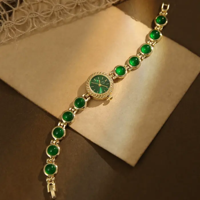 Montre vintage pour femme en or et pierres vertes